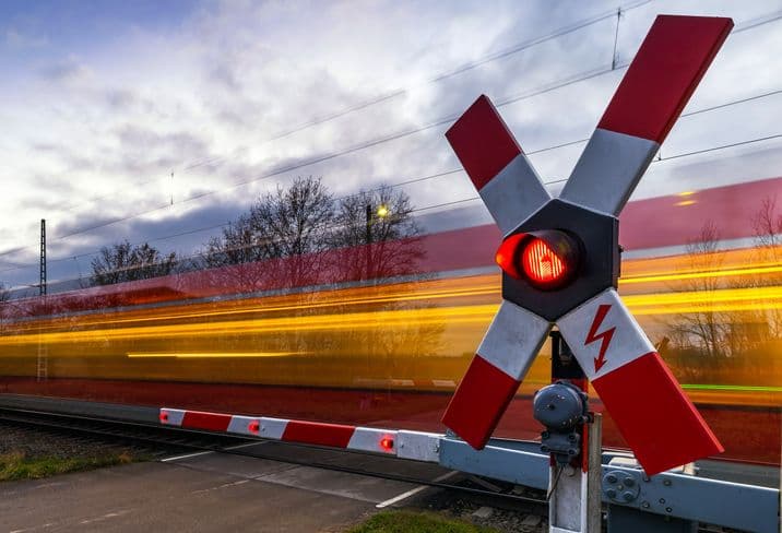 The red blur of a train rushing past a railroad crossing.