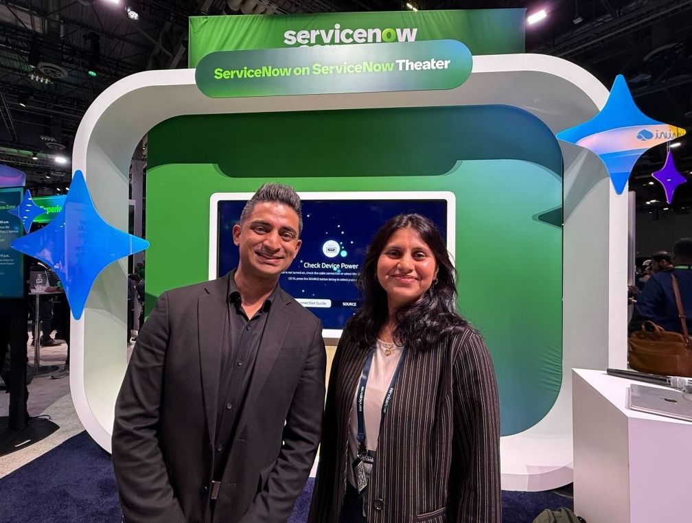 Two people standing in front of a large display at a technology conference booth