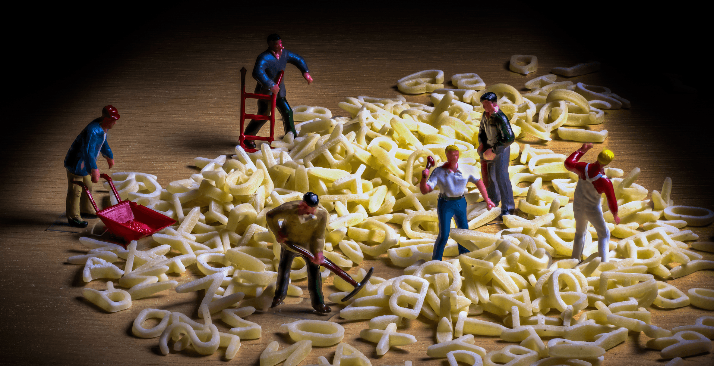 Una foto di figurine in miniatura che raffigurano operai muniti di picconi e carriole mentre scavano in un cumulo di lettere che formano una “zuppa di lettere”.