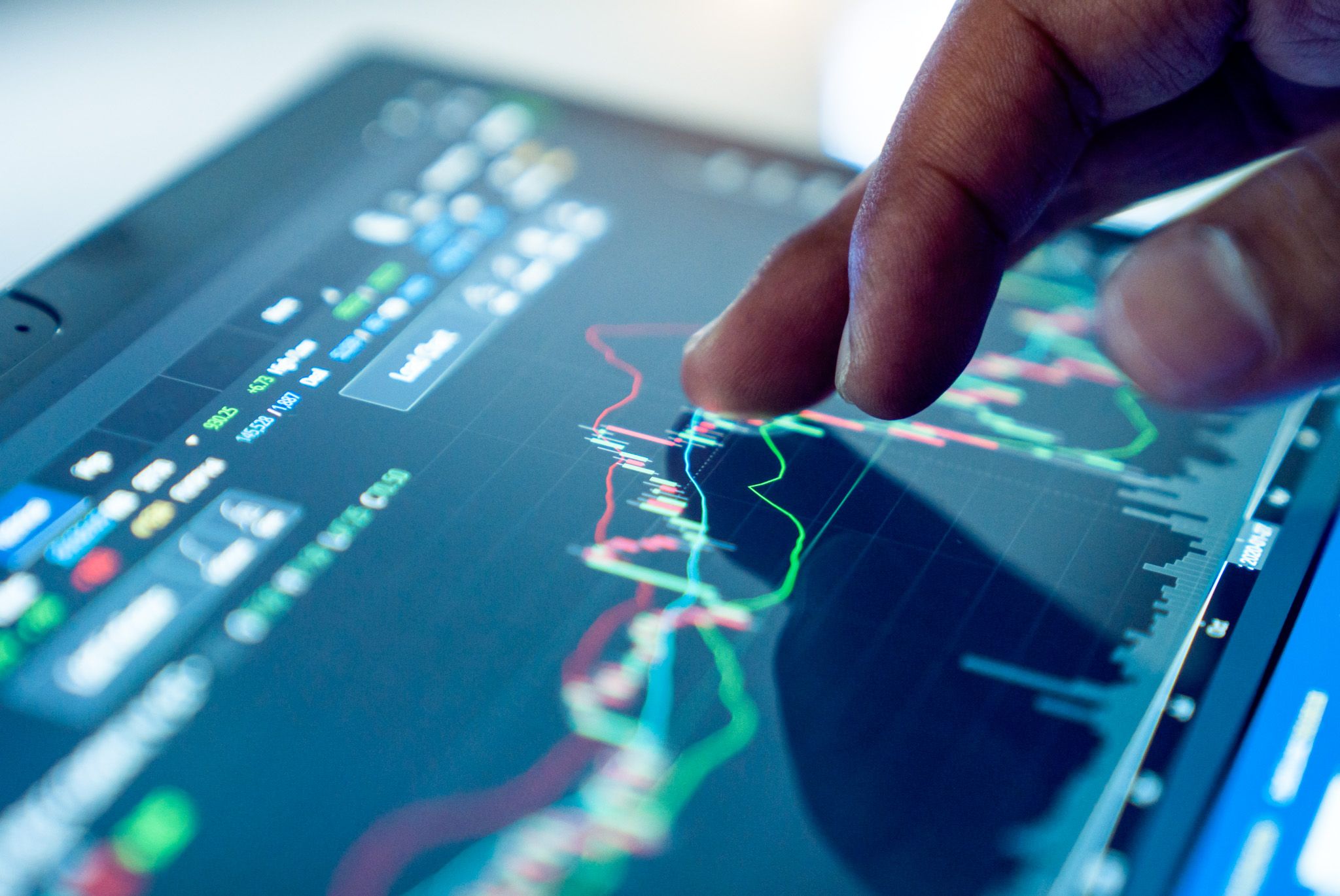 Analisi di mercato: un dito indica grafici finanziari su uno schermo touch