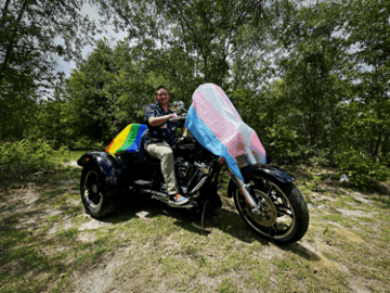 Persona in sella a una motocicletta con un tessuto colorato che sventola al vento