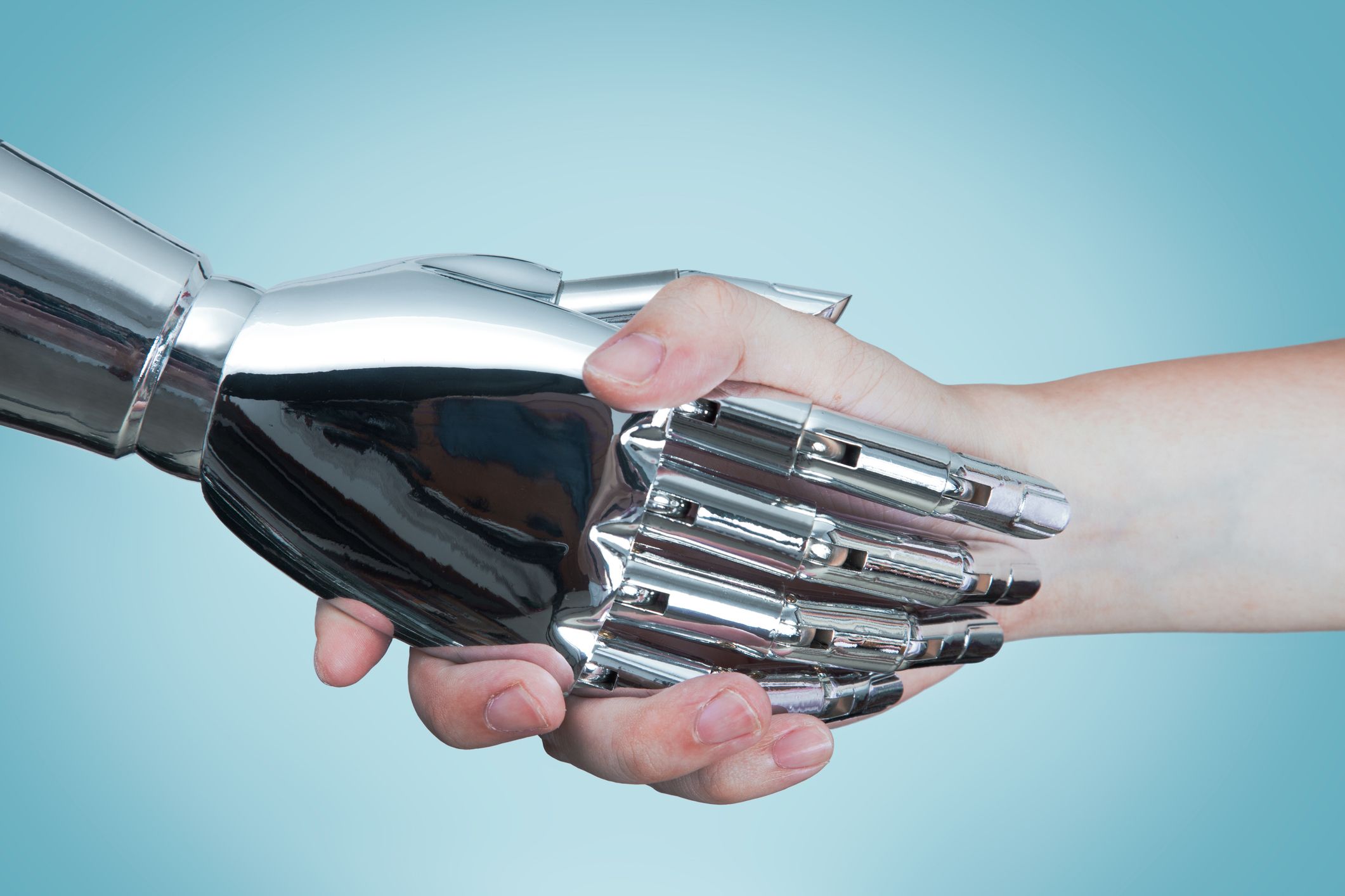 Una foto in primo piano di un’ handshake e tra un robot dotato di intelligenza artificiale e un essere umano.