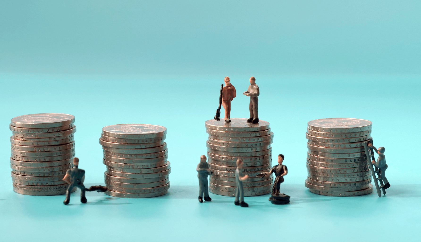 Miniature toy figures of laborers stand beside towers of silver coins.