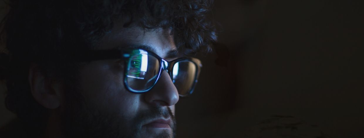 immagine stock: volto in una stanza buia illuminato dal bagliore di un monitor del computer