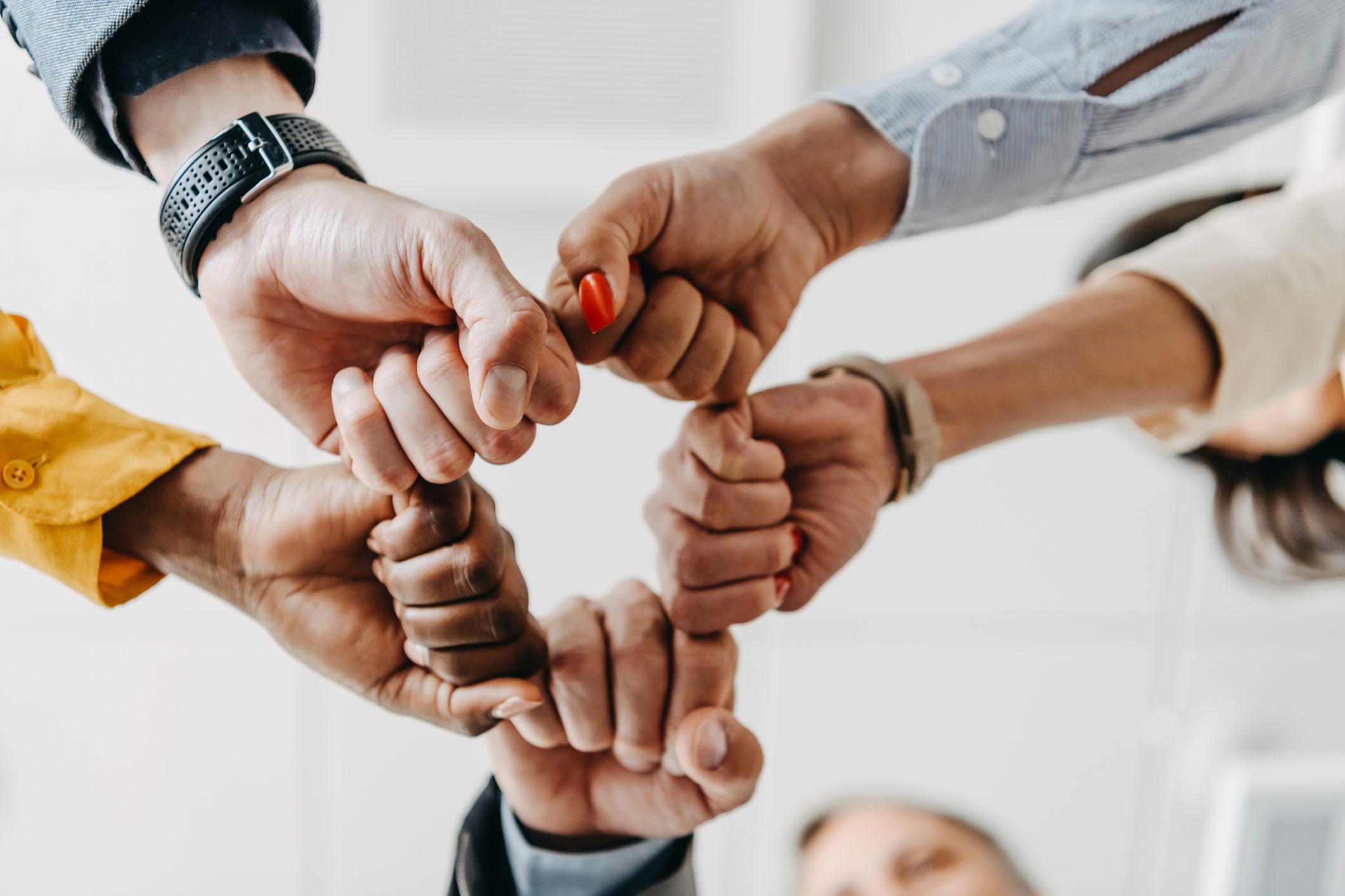 Un gruppo di cinque lavoratori d'ufficio multietnici che fanno un pugno collettivo
