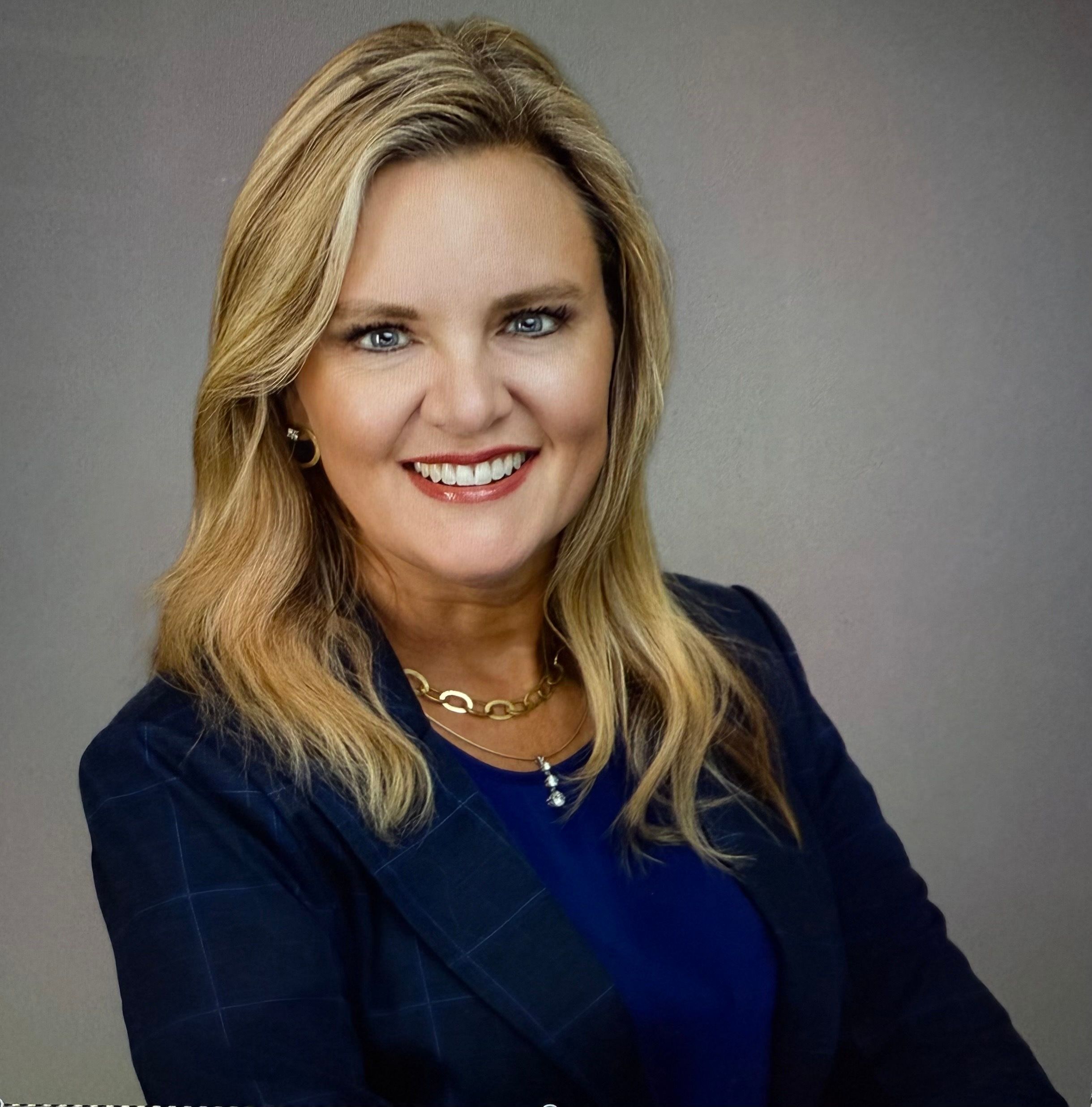 Professional headshot of woman with blonde hair in dark blazer